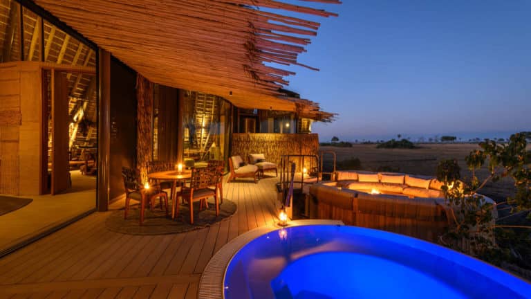 Jao Camp's brilliantly lit swimming pool and fire pit at twilight