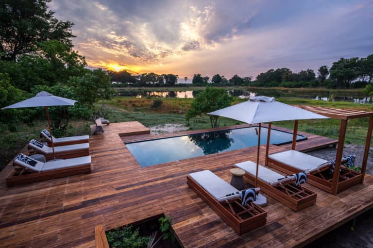 Wooden deck area boasting sparkling pool and sun loungers at Qorokwe