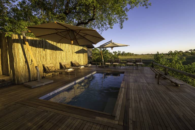 Shaded main pool deck at Savuti Camp with distant landscape view